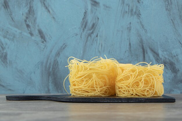 Тонкие спагетти-гнезда на деревянной доске