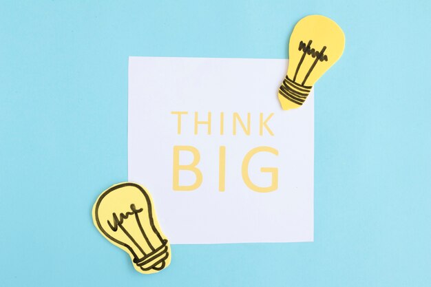 Free photo think big text on white paper with light bulbs on blue background