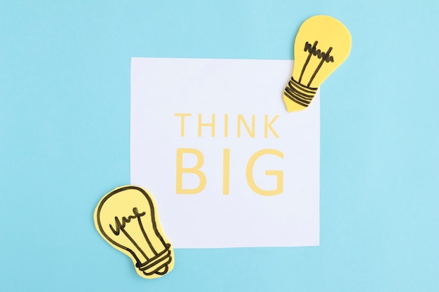 Think big text on white paper with light bulbs on blue background
