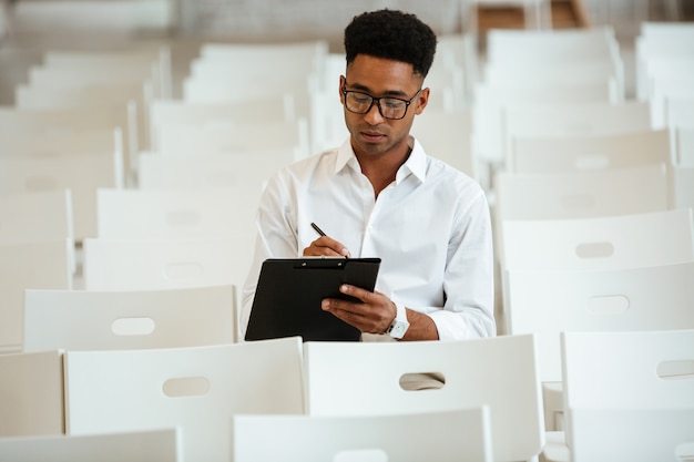 Coworking di seduta di pensiero dell'uomo africano con la lavagna per appunti