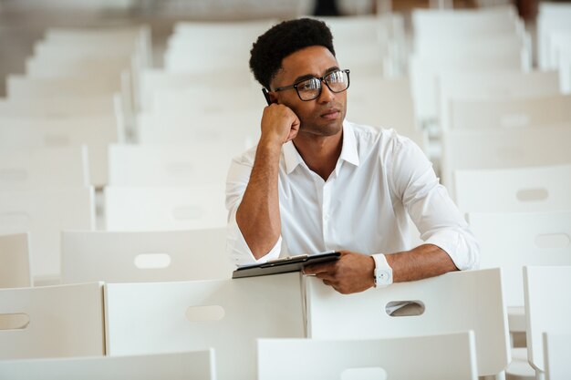 Thinking african man sitting coworking with clipboard