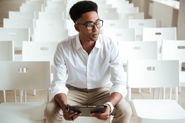 Thinking african man sitting coworking with clipboard