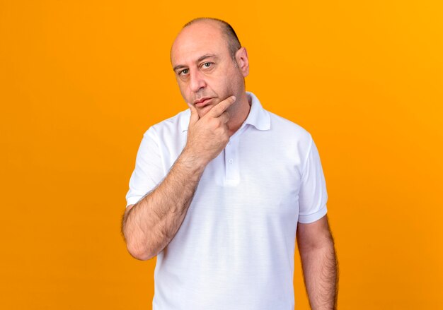 Thinking casual mature man grabbed chin isolated on yellow wall