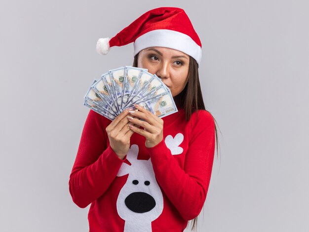 Thinking looking side young asian girl wearing christmas hat with sweater holding cash isolated on white background