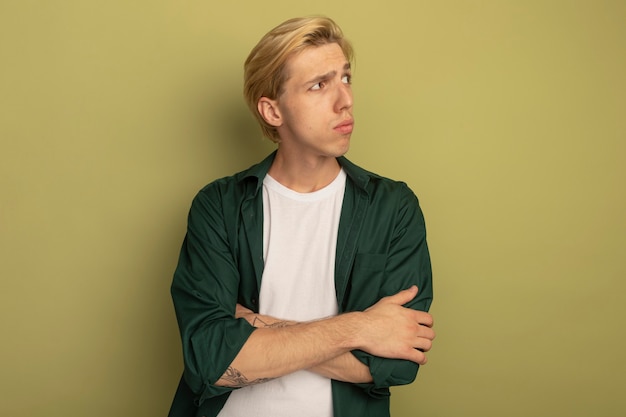 Free photo thinking looking at side young blonde guy wearing green t-shirt crossing hands