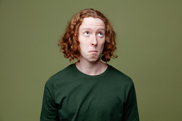 Thinking looking at side young handsome guy wearing green t shirt isolated on green background