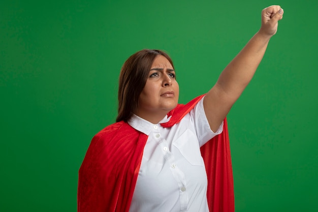 Free photo thinking middle-aged superhero female looking up raising fist isolated on green background