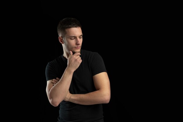 Thinking. Monochrome portrait of young caucasian man isolated on black wall.