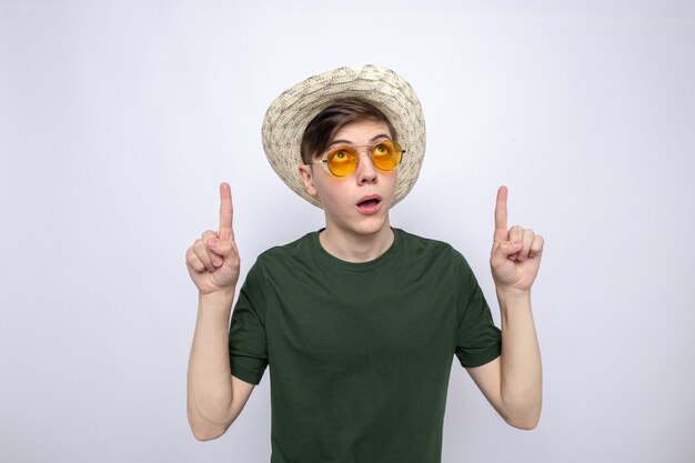 Thinking points at up young handsome guy wearing hat with glasses 