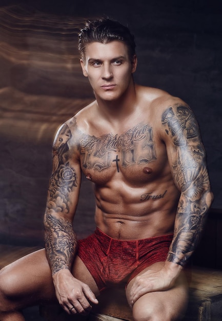 Thinking shirtless muscular man with tattooes on his body.