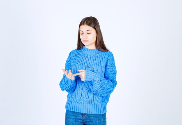 thinking woman in blue sweater standing on white.