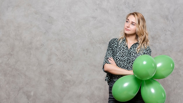 Thinking woman holding a bunch of balloons