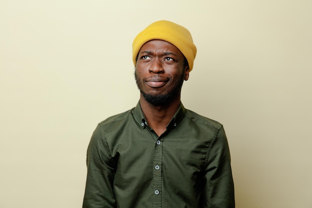 Thinking young african american male in hat wearing green shirt isoloated on white background