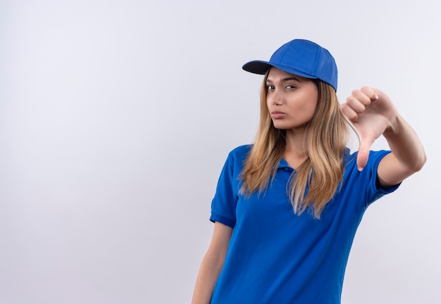 Бесплатное фото Думающая молодая доставщица в синей униформе и закрывает большой палец вниз на белой стене с копией пространства