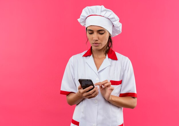 Thinking young female cook wearing chef uniform dial number on phone with copy space