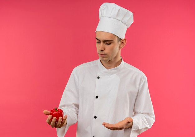 Thinking young male cook wearing chef uniform holding and looking at papper