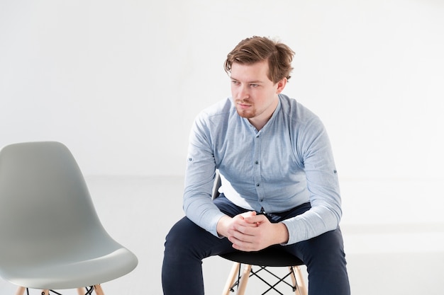 Free photo thinking young man sitting on a chair