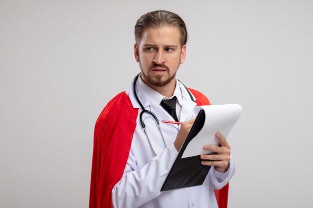 Думающий молодой супергерой смотрит в сторону в медицинском халате со стетоскопом, держащим ручку