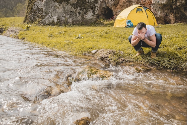 Foto gratuita l'escursionista assetato che beve acqua dal fiume