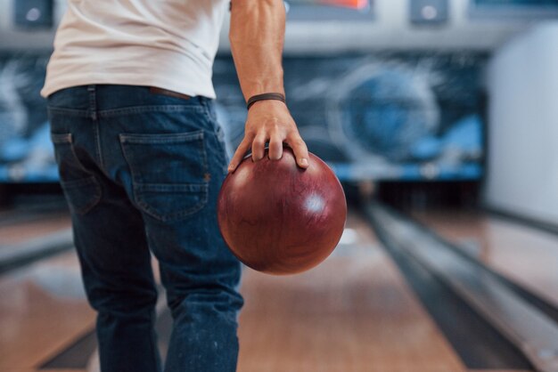 This is gonna be the strike. Rear particle view of man in casual clothes playing bowling in the club