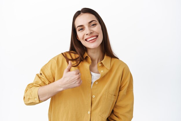 This is great. Smiling good-looking woman shows thumb up in approval, agree or like something, praise awesome work, well done, proud of you gesture, standing over white background