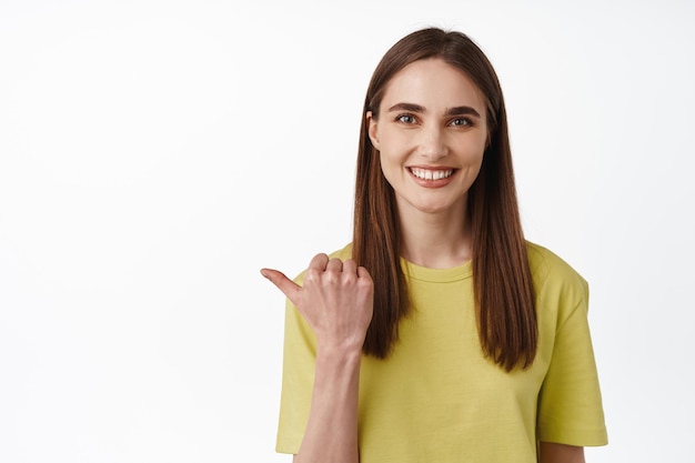 This way. Portrait of beautiful smiling woman pointing left, showing direction, provide information, recommending click on link, check it out, white background
