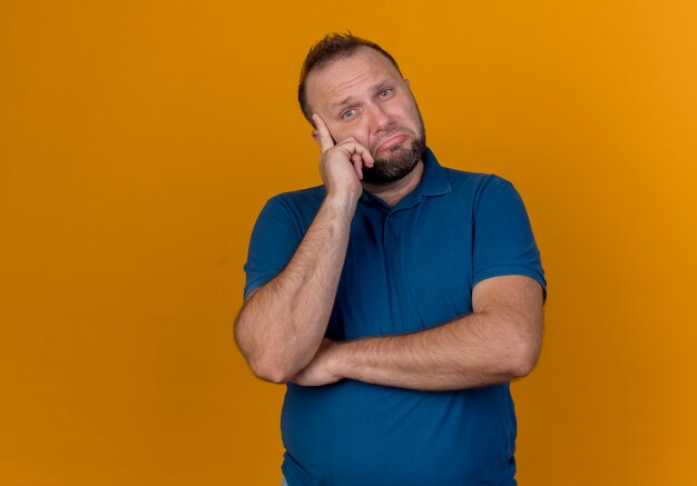 Thoughtful adult slavic man putting finger on temple 