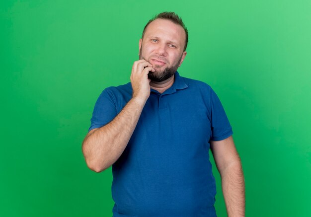 Thoughtful adult slavic man  touching chin isolated on green wall with copy space
