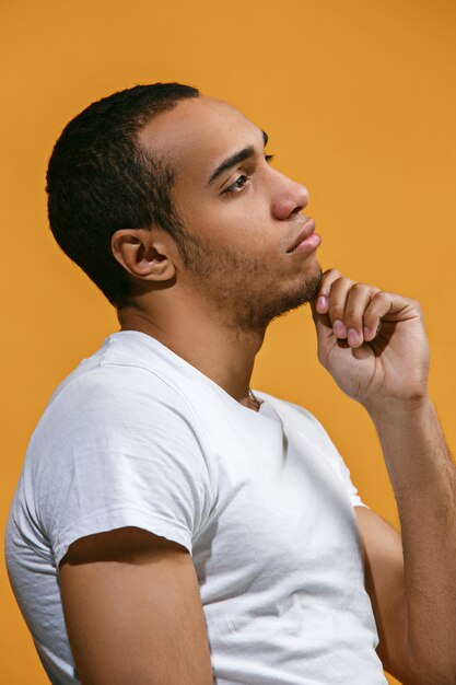 Thoughtful Afro-American man is looking thoughtfully against orange