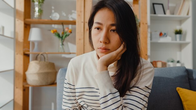 Thoughtful asian lady sit with feel lonely, feeling depressed and spending time alone stay at home