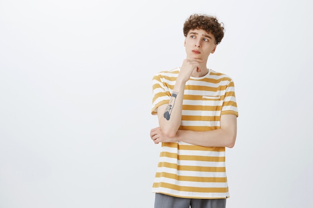 Thoughtful attractive teenage guy posing against the white wall