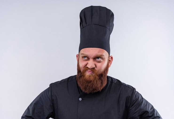 Free Photo a thoughtful bearded chef man in black uniform thinking while looking up on a white wall