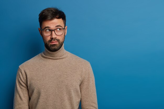 Thoughtful bearded guy focused above with unaware expression