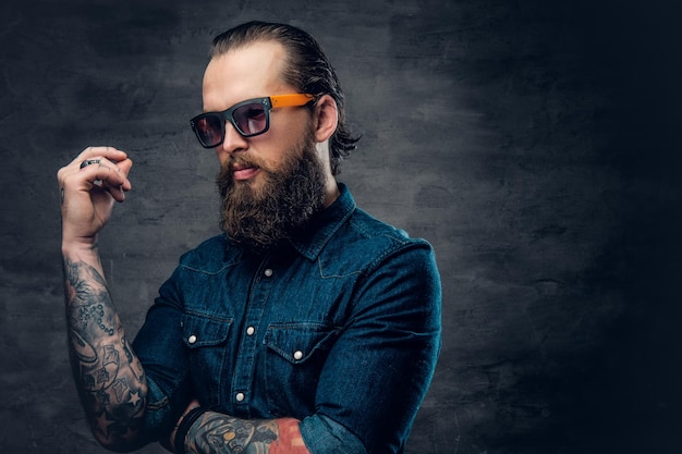 Free photo thoughtful bearded male in sunglasses with tattoos on his arms.