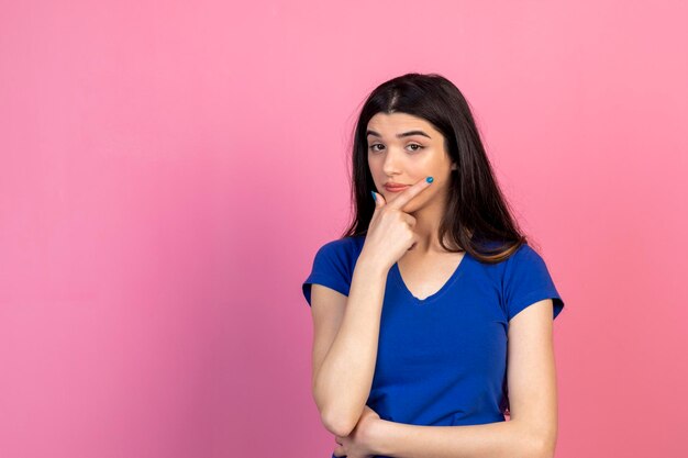 Thoughtful beautiful woman holding her hand to her chin and thinking High quality photo