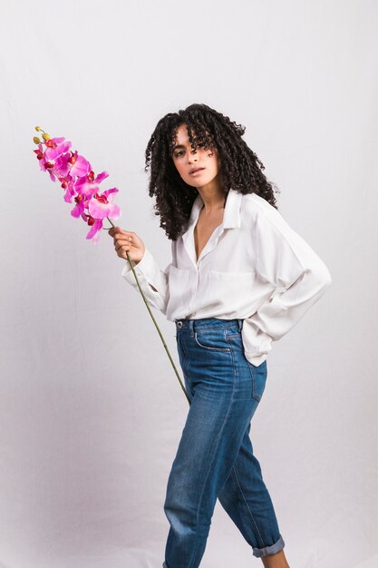 Thoughtful black woman holding big pink flower 