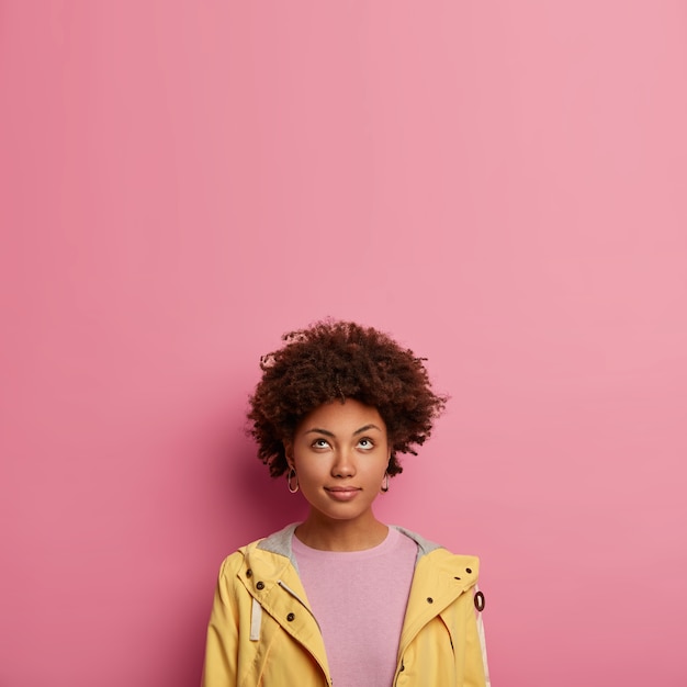 Free photo thoughtful black woman with curly hair looks attentively above