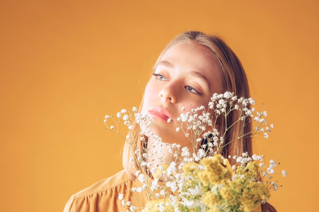 Thoughtful blond woman standing with flowers bouquet 