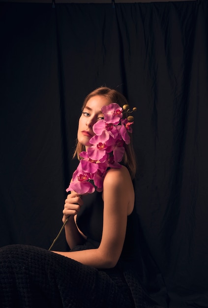 Foto gratuita donna bionda premurosa con fiore rosa