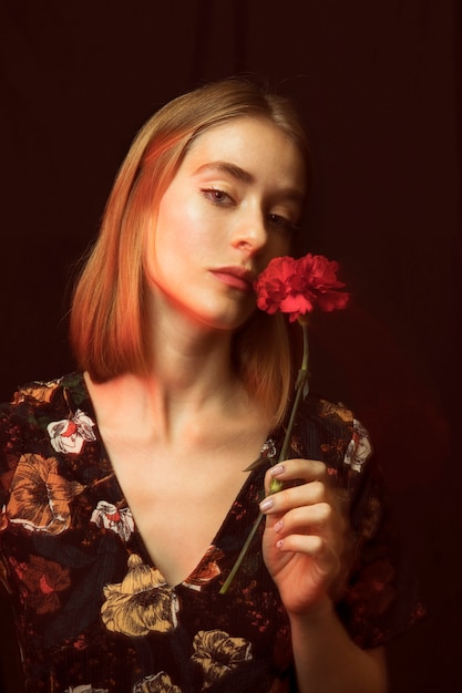 Thoughtful blond woman with red carnation 