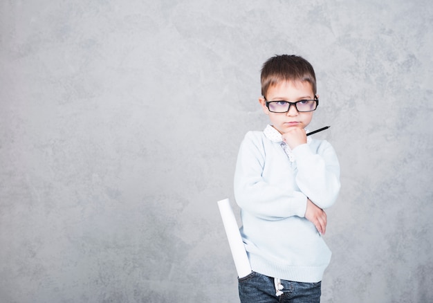 Thoughtful boy architect with paper roll in pocket