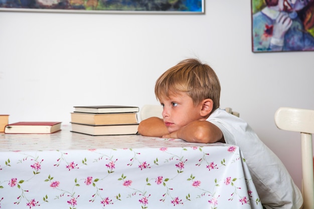 テーブルに座っている思いやりのある少年