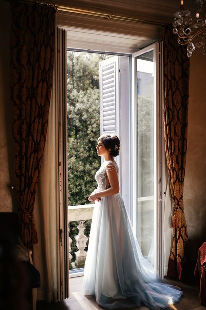 Задумчивая невеста стоит перед открытым окном по утрам