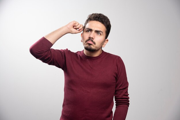 A thoughtful brunette man standing and posing