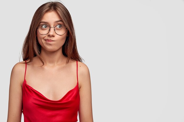 thoughtful brunette young woman posing against the white wall