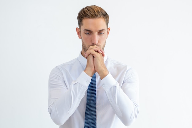 Thoughtful business man thinking hard with his hands clasped