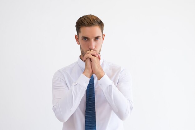 Thoughtful business man touching mouth with clenched hands