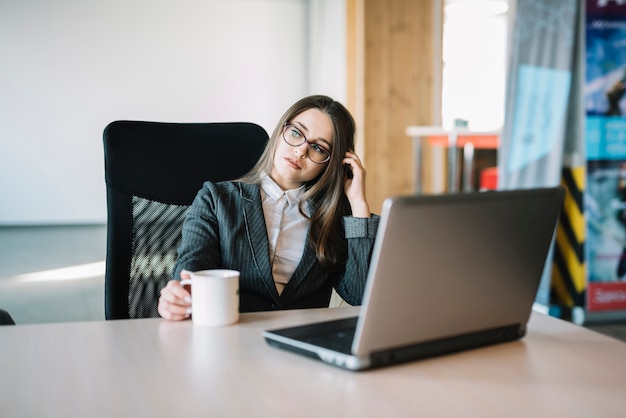 Thoughtful business woman sitting at table with laptop