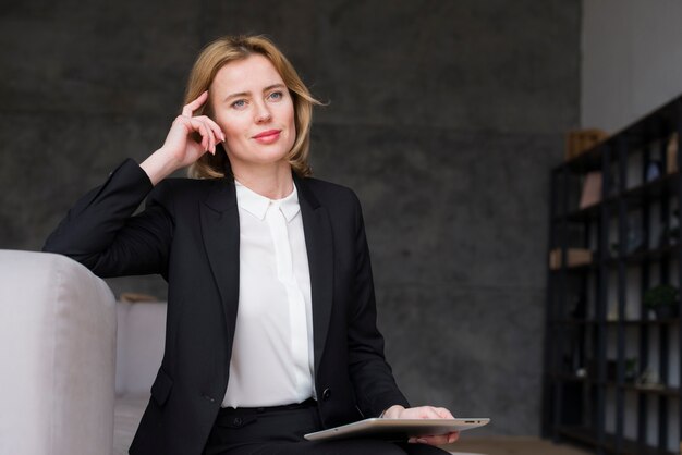 Thoughtful business woman sitting with tablet