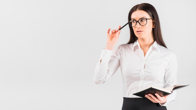 Thoughtful business woman standing with notebook 